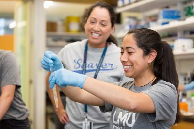 Two Seaver College students working in a lab, holding a pipettte