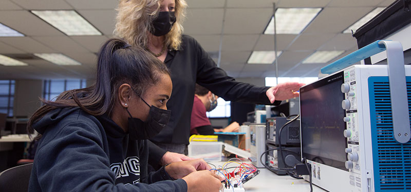 A professor assisting a student with building a radio