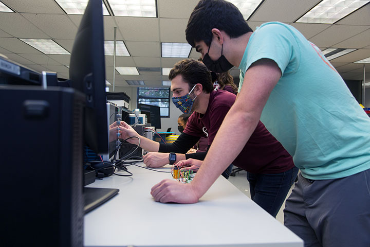 Two students testing a circuit board