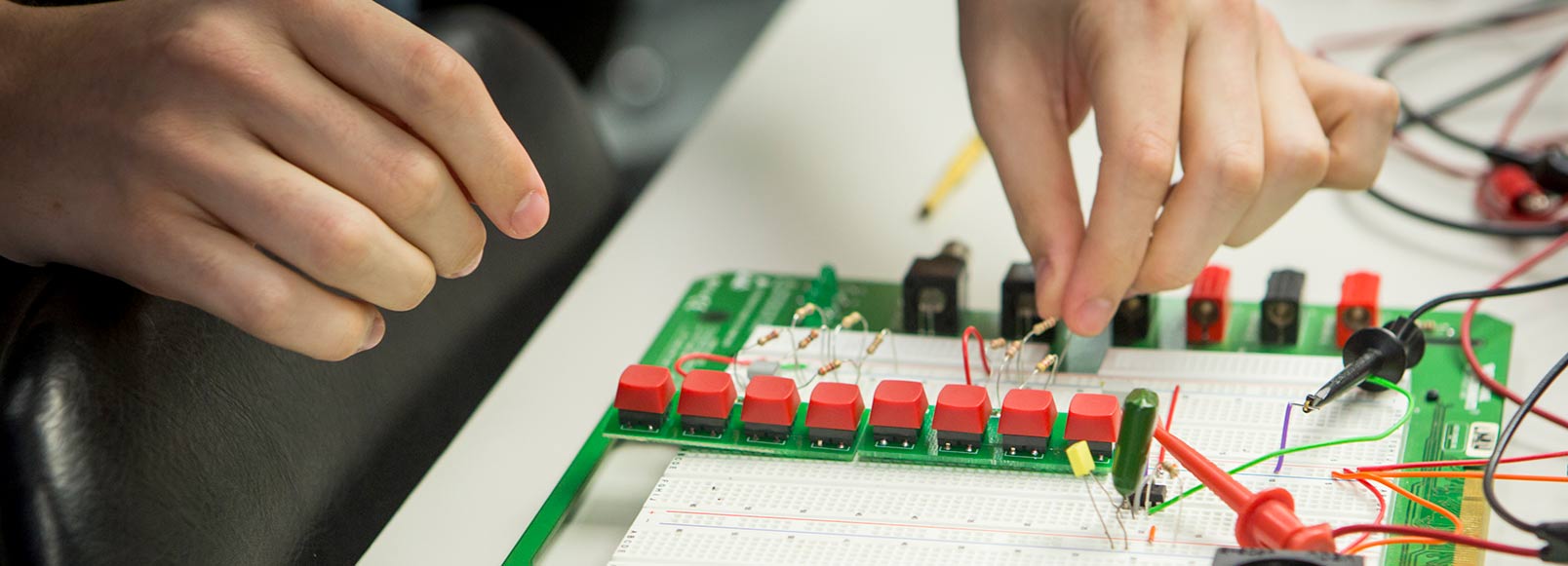 Close up of student's hands working on circuit board