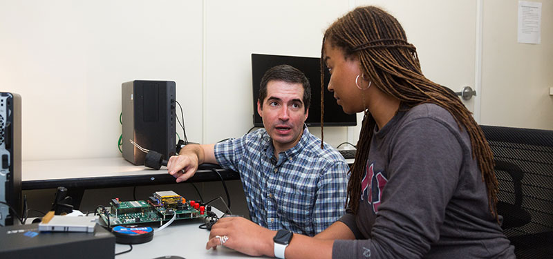 An instructor explaining an aspect of a circuit board to a student