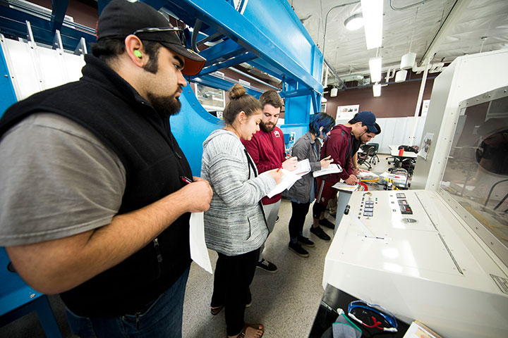 Students working with a heavy piece of machinery