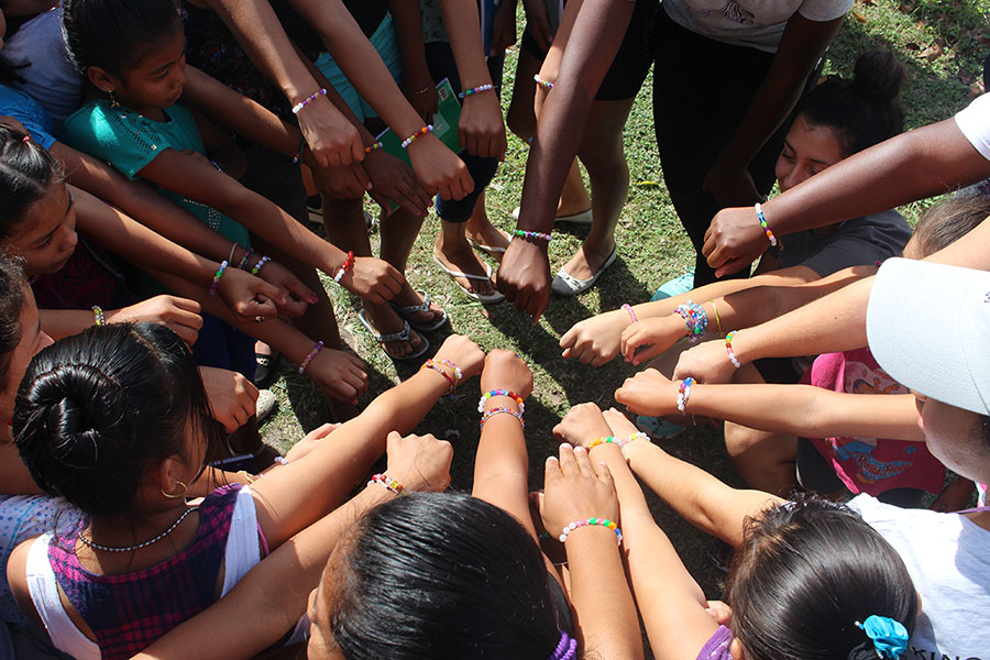 A large group of kids putting their hands into a big circle